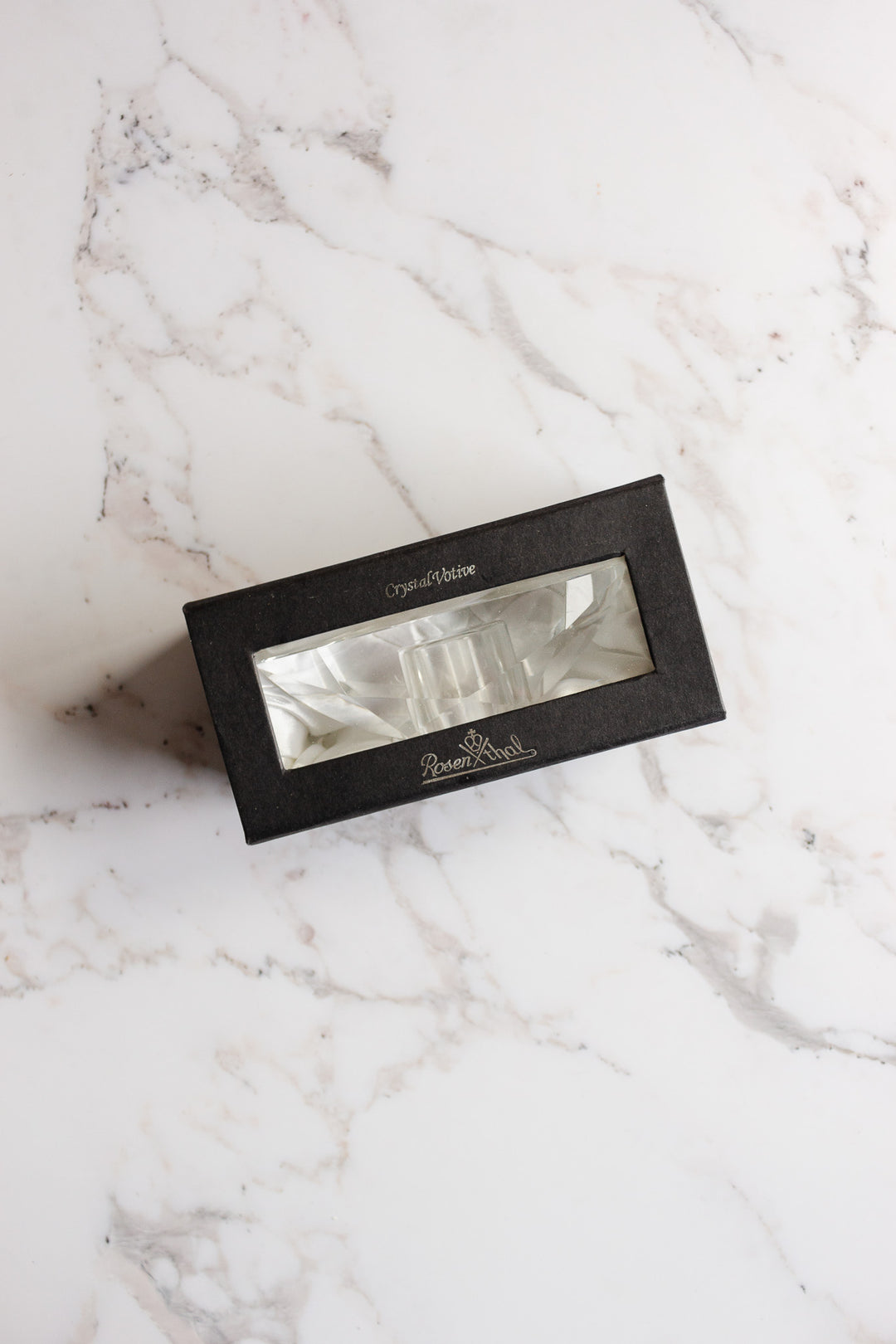 A black rectangular box with a clear window showcases a vintage Rosenthal crystal votive inside, resting on white marble. The box is labeled Crystal Critter and Resem Blest, reflecting Rosenthal's signature elegance.