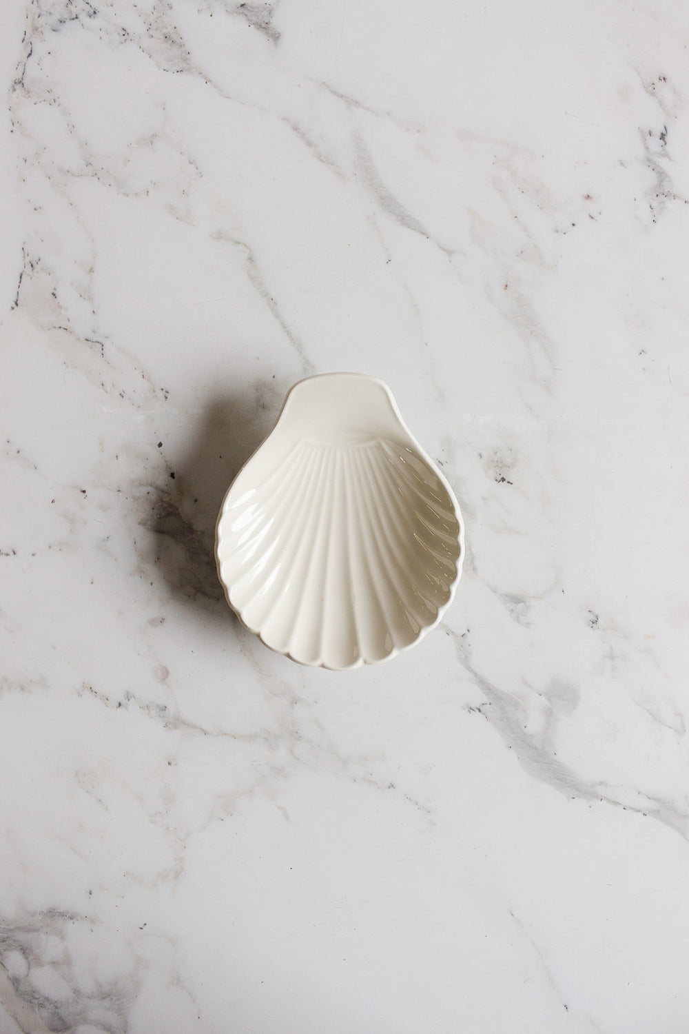 The vintage English Lord Nelson Pottery shell catch all, in classic white, is elegantly displayed on a marble surface.