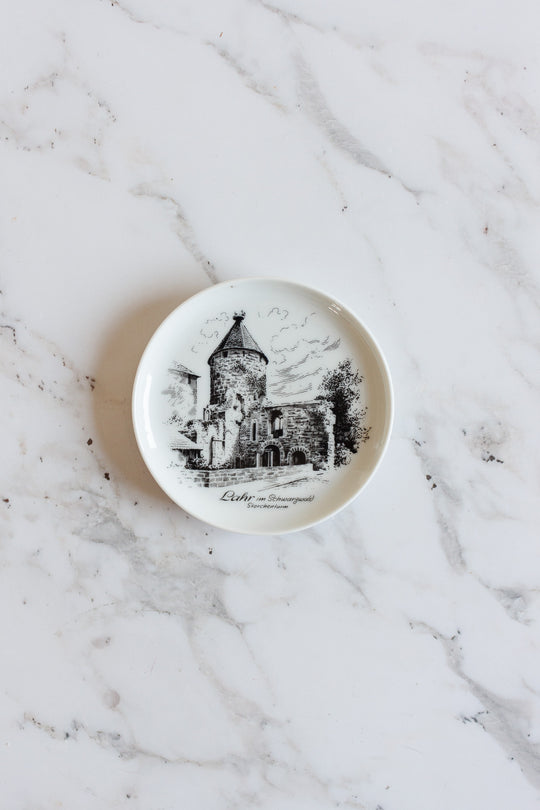 A small white vintage Kaiser Germany porcelain plate with a black illustration of a historic stone building and trees, placed on marble. This charming souvenir catch all features text beneath the image—perfect for your home.