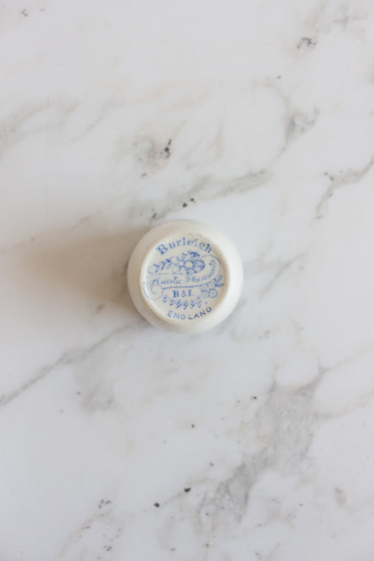 A pair of rare antique Burleigh Asiatic Pheasants egg cups rest on a white marble surface, showcasing classic blue floral patterns reminiscent of vintage English pottery.