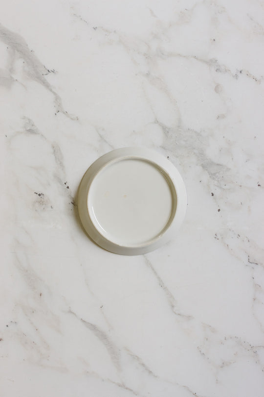 A german coasters set, featuring a plain white minimalist design, sits centered on a white marble surface with gray veining. The coasters appear clean and empty.