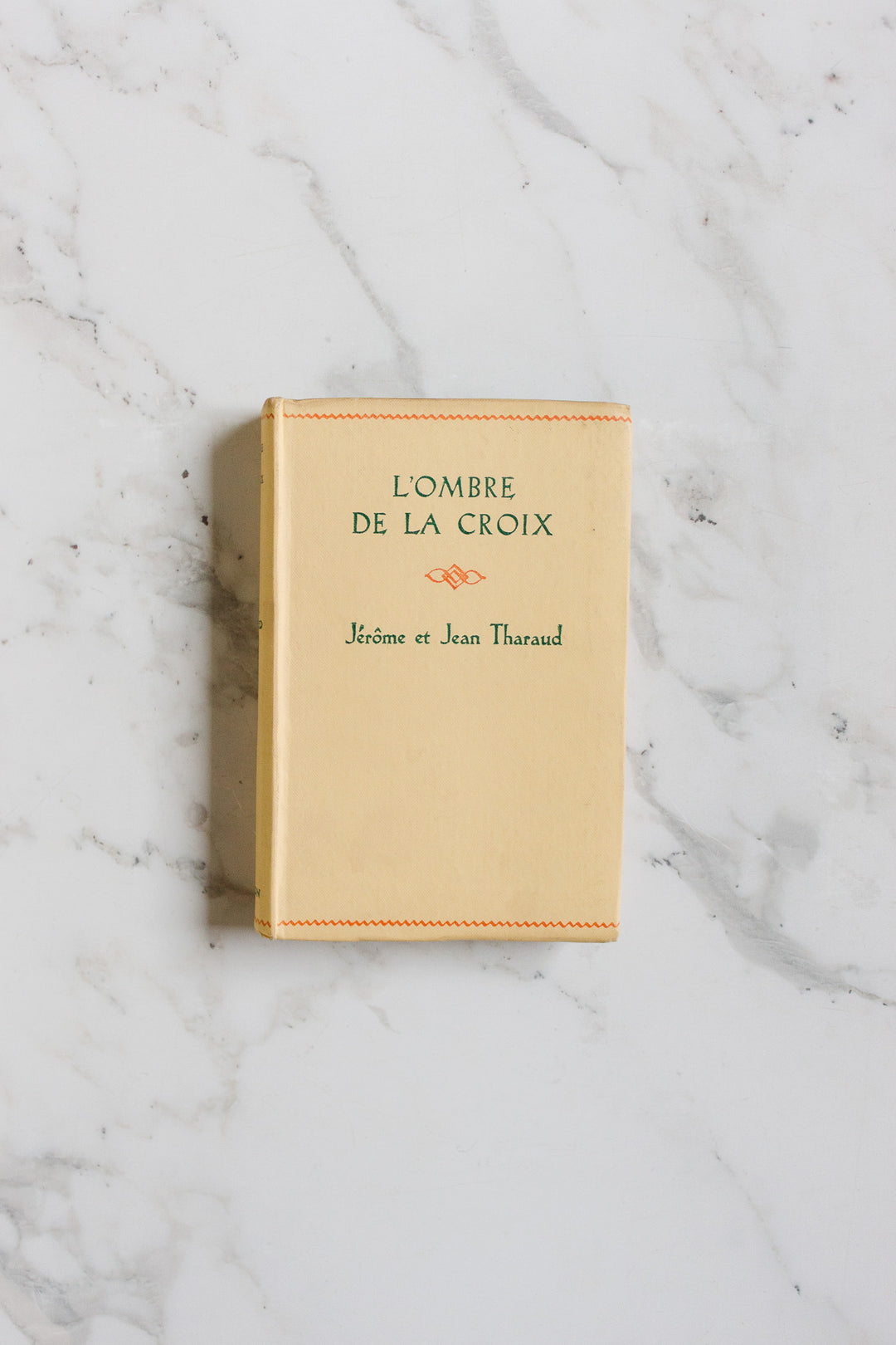 A beige book from the books collection rests on a white marble surface, its dimensions enhancing the elegant simplicity of the scene.