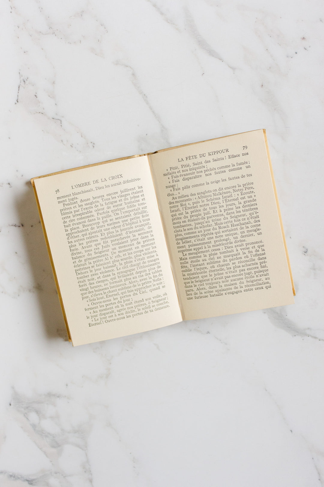 An open book from the "books" collection rests on a white marble surface, revealing French text with headings at the top of each page. The cover and exact measurements are not visible in the image.
