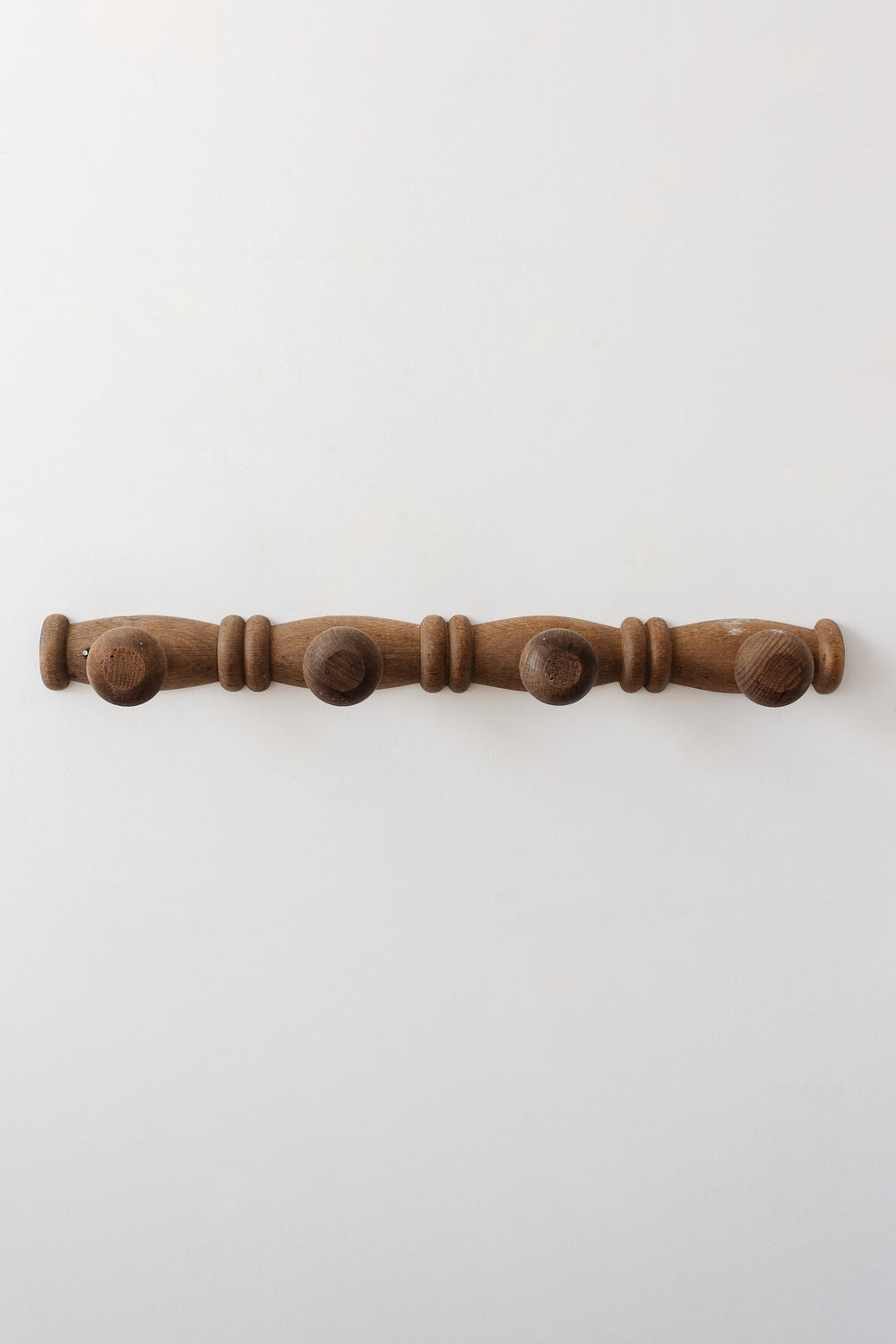 The antique French faux bamboo 4 prong patère, mounted on a plain white wall, brings a touch of vintage French decor to your space.