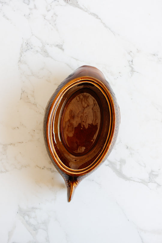 The fish soupiere, a brown ceramic gravy boat with handle and spout, is shown from above on a white marble surface—its size ideal for serving sauces at any meal.