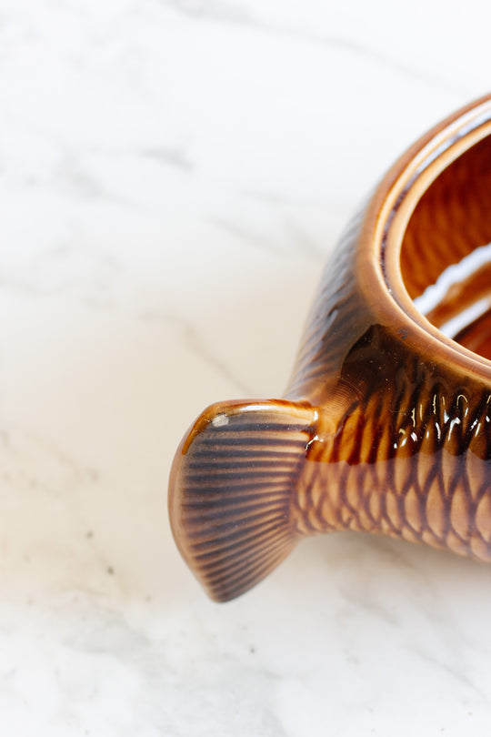 Close-up of the brown ceramic Fish Soupiere, featuring detailed scales and tail on a white marble surface—perfect for adding unique style and dimension to your table setting.