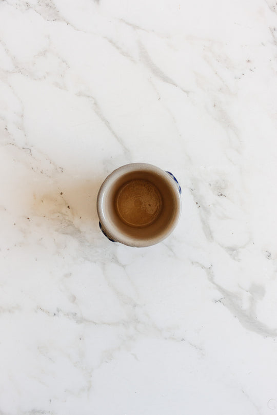 A minimalist salt cellar, compact and empty, is viewed from above on a white marble surface with light gray veining.