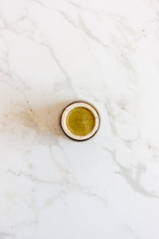 A compact drinkware set filled with greenish-yellow liquid is seen from above on a white marble surface, showcasing its vibrant color and sleek design.
