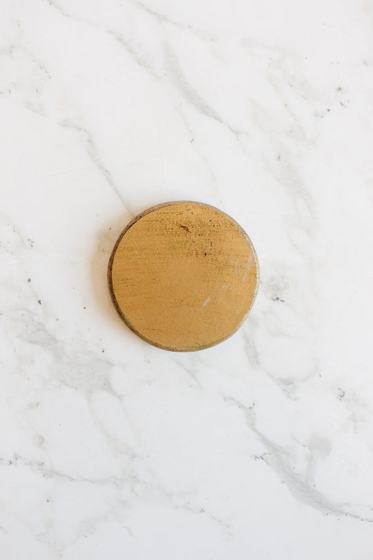 A set of round gold Florentine coasters with sleek dimensions rests elegantly on a marble surface.